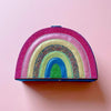 Colorful rainbow-shaped pouch on a pink background