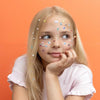 Young girl with stickers on her face against an orange background