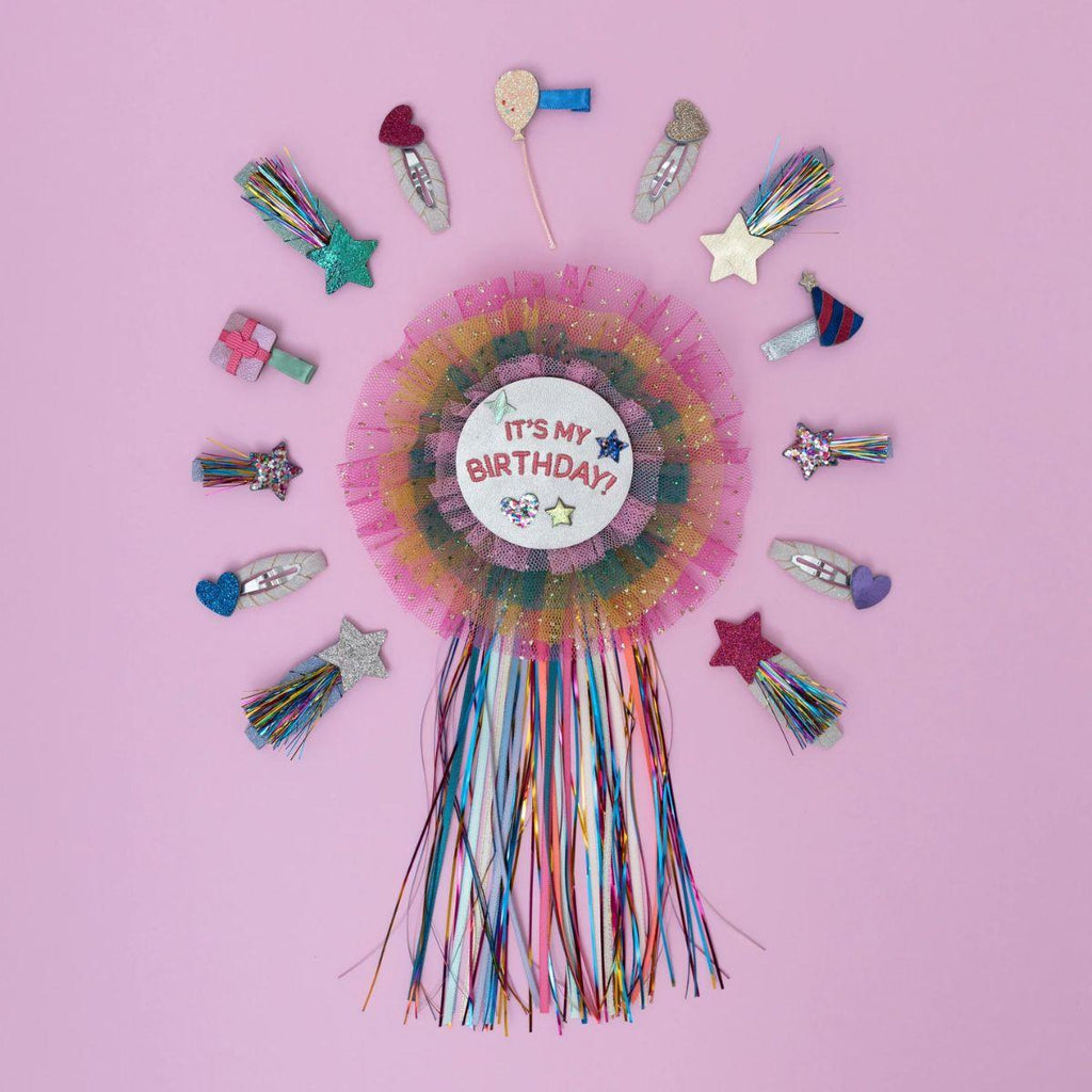 Colorful birthday rosette with decorative hair clips on a pink background