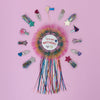 Colorful birthday rosette with decorative hair clips on a pink background