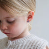 Close-up of a young girl wearing a blue earring with a neutral background