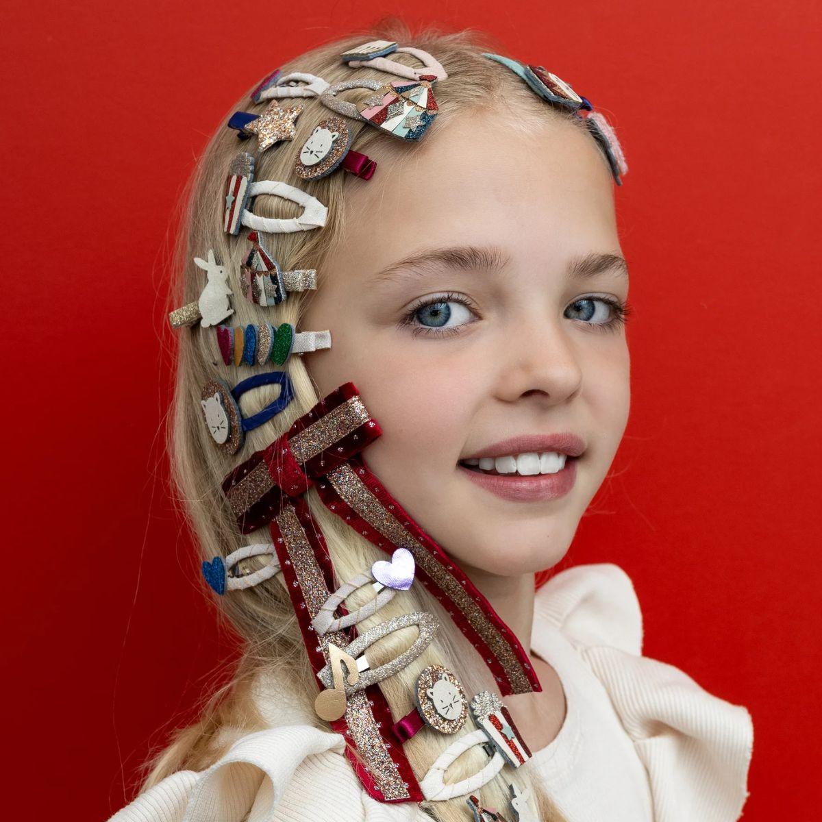 Young girl with a variety of decorative hair accessories on a red background