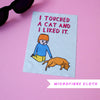 Microfibre cloth with a cartoon design of a boy and cat, text 'I touched a cat and I liked it.' on a pink background.