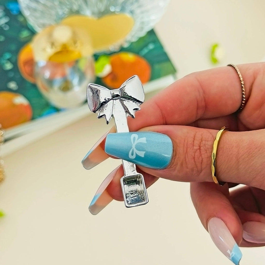 Hand holding a silver bow-shaped object with a blurred background