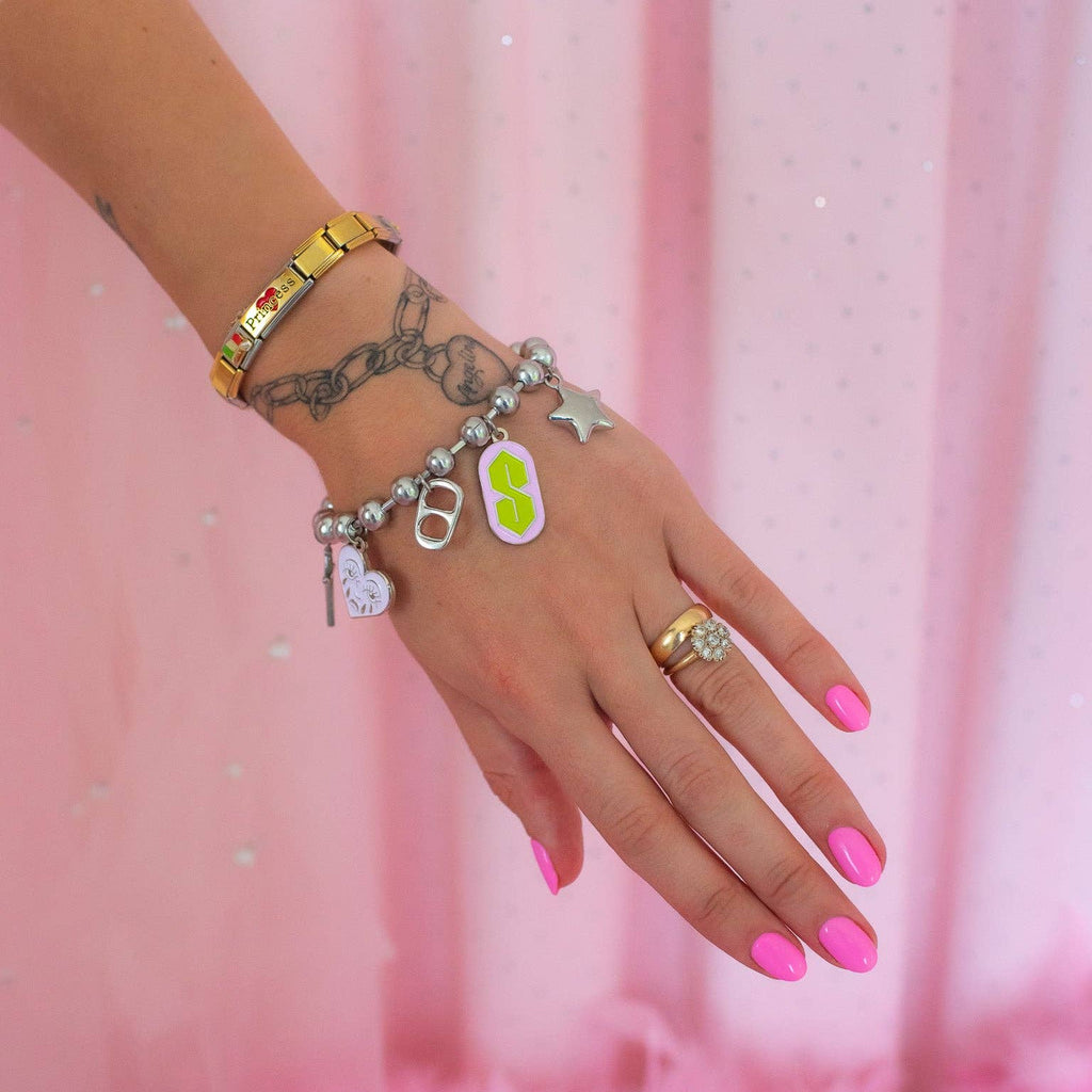 Hand with multiple bracelets and rings on a pink background