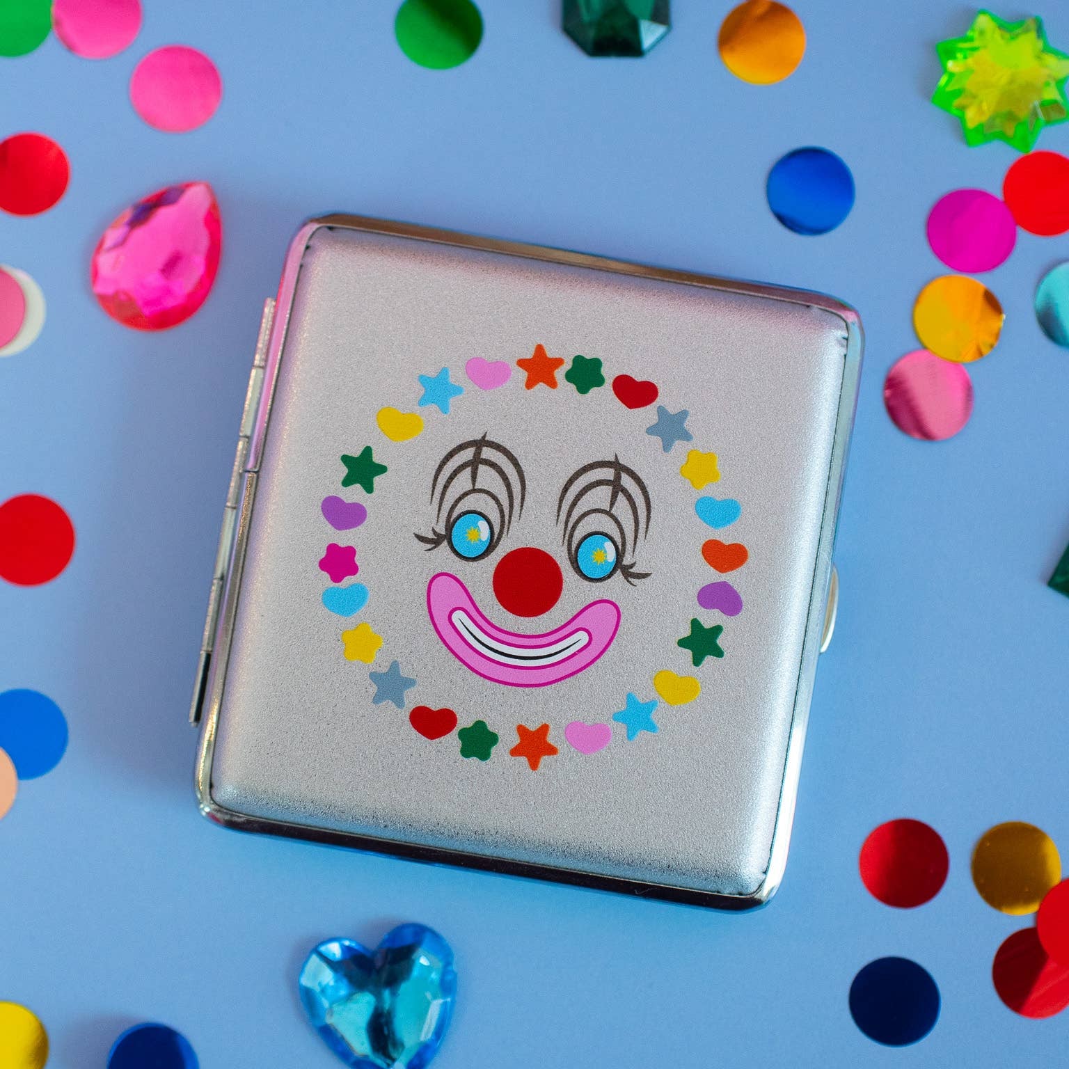Cigarette case with clown face design on a blue background with colorful confetti