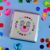 Cigarette case with clown face design on a blue background with colorful confetti