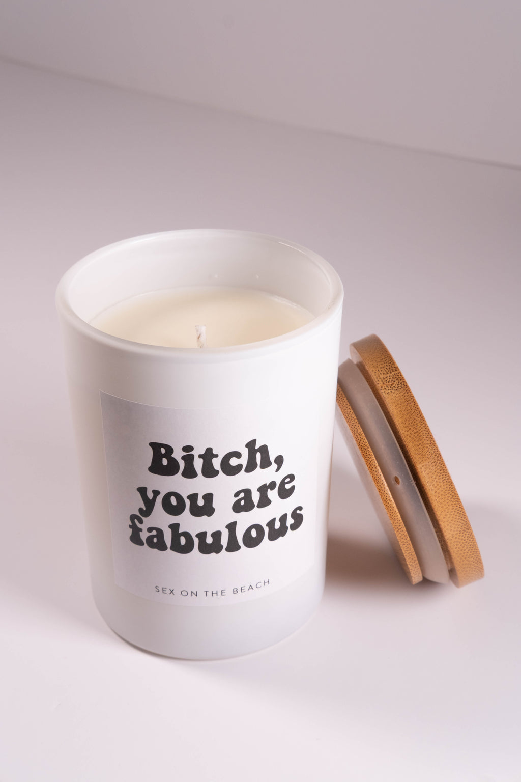 Candle in a white container with 'Bitch, you are fabulous' text on a light background