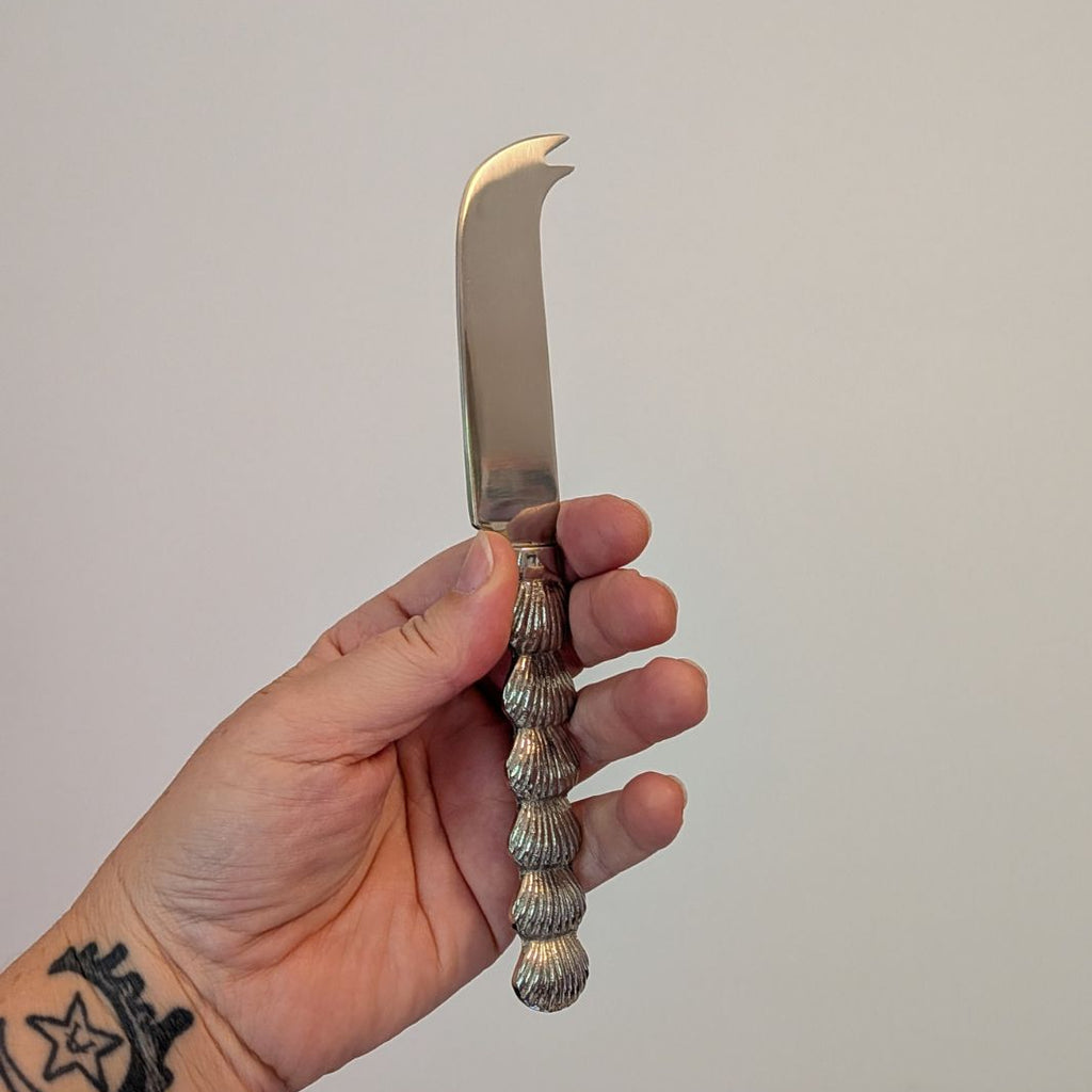 Hand holding a decorative knife against a plain background