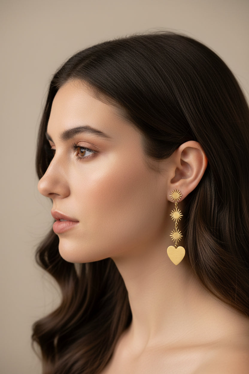 Brass Gold heart and sun-shaped earrings on a dark background