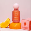 Evaliah perfume bottle and packaging on a pink background with an orange slice.
