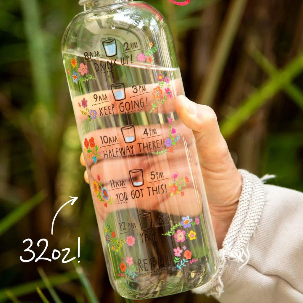 Hand holding a 32oz motivational water bottle with time markers and floral designs.