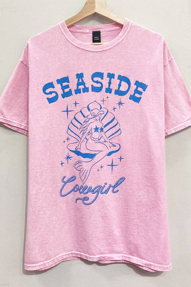 Pink t-shirt with 'Seaside Cowgirl' graphic design on a hanger.