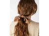 Person with a ponytail held by a floral scrunchie against a white background