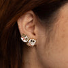 Close-up of an ear wearing gold earrings with cat and dog designs.