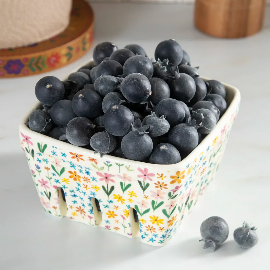 Blueberries in a floral-patterned basket on a white surface
