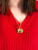 Gold ravioli locket necklace with a square pendant on a red sweater