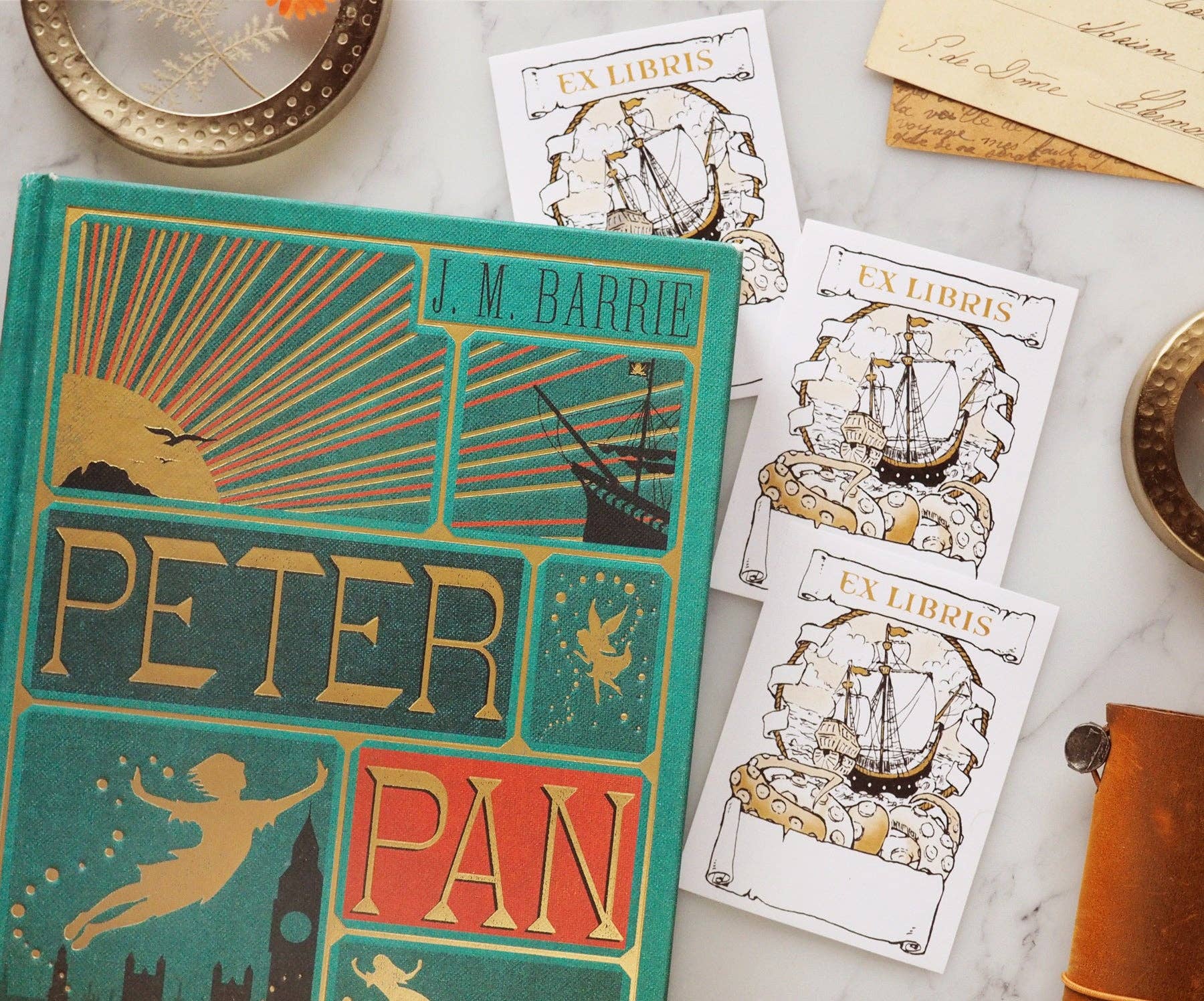 Vintage 'Peter Pan' book with decorative ex libris labels on a marble surface