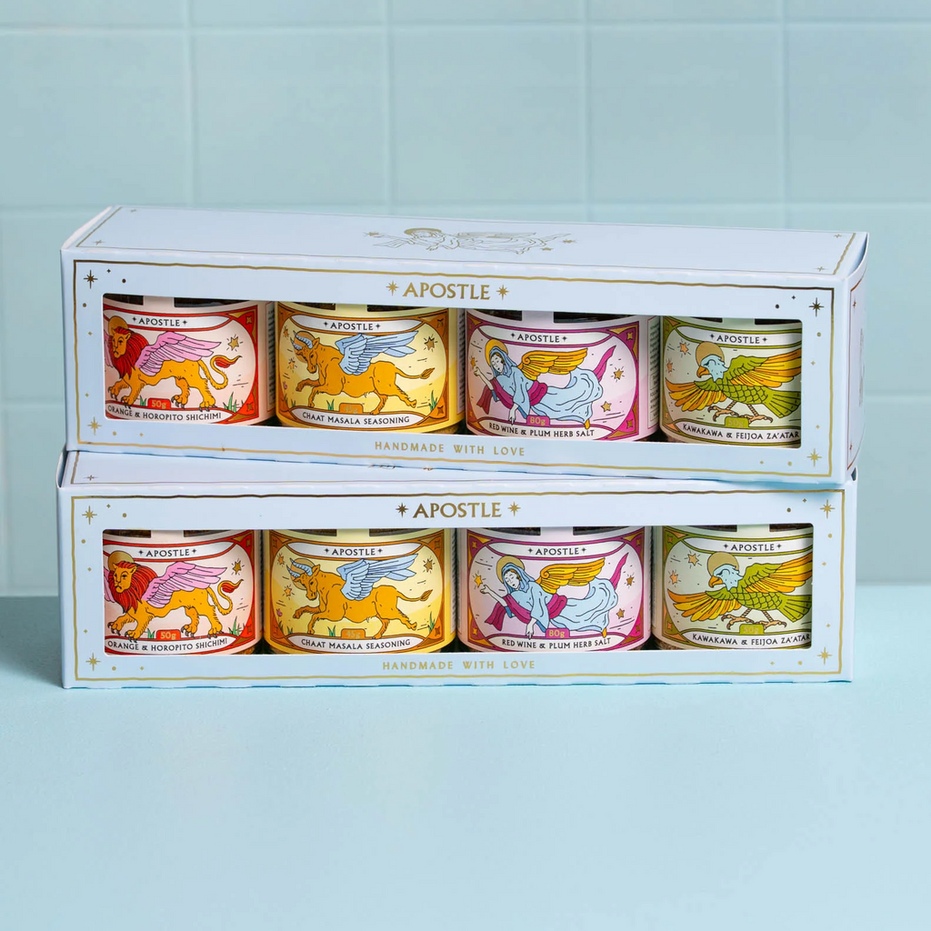 Set of candles in decorative tins with colorful labels on a light blue background