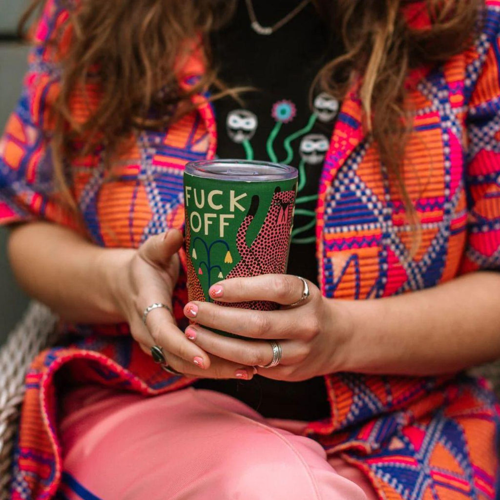 Person holding a tumbler with a graphic design and text (fuck off)