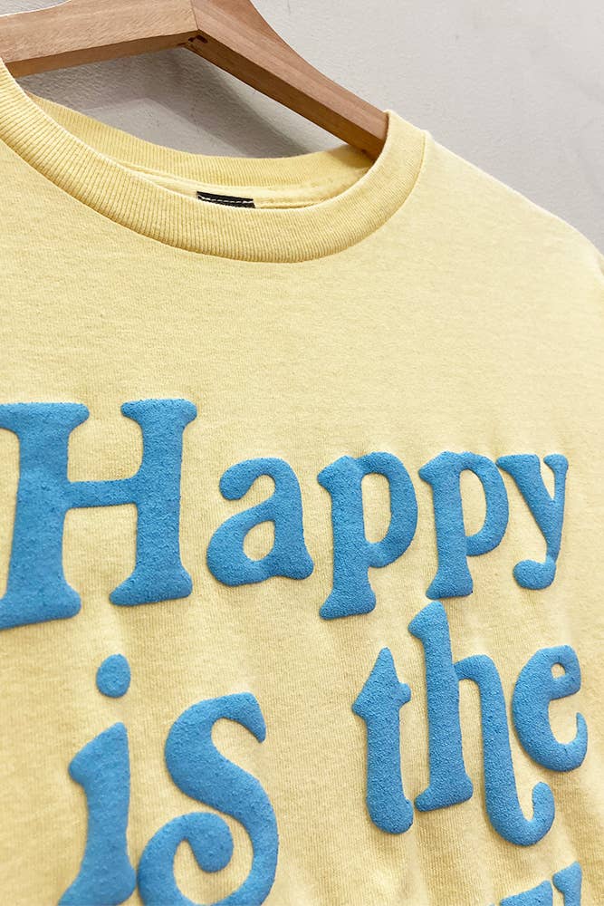 Yellow sweatshirt with blue text 'Happy is the' on a hanger against a gray background