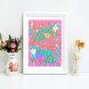 Framed artwork of cats among flowers on a white surface with decorative items.