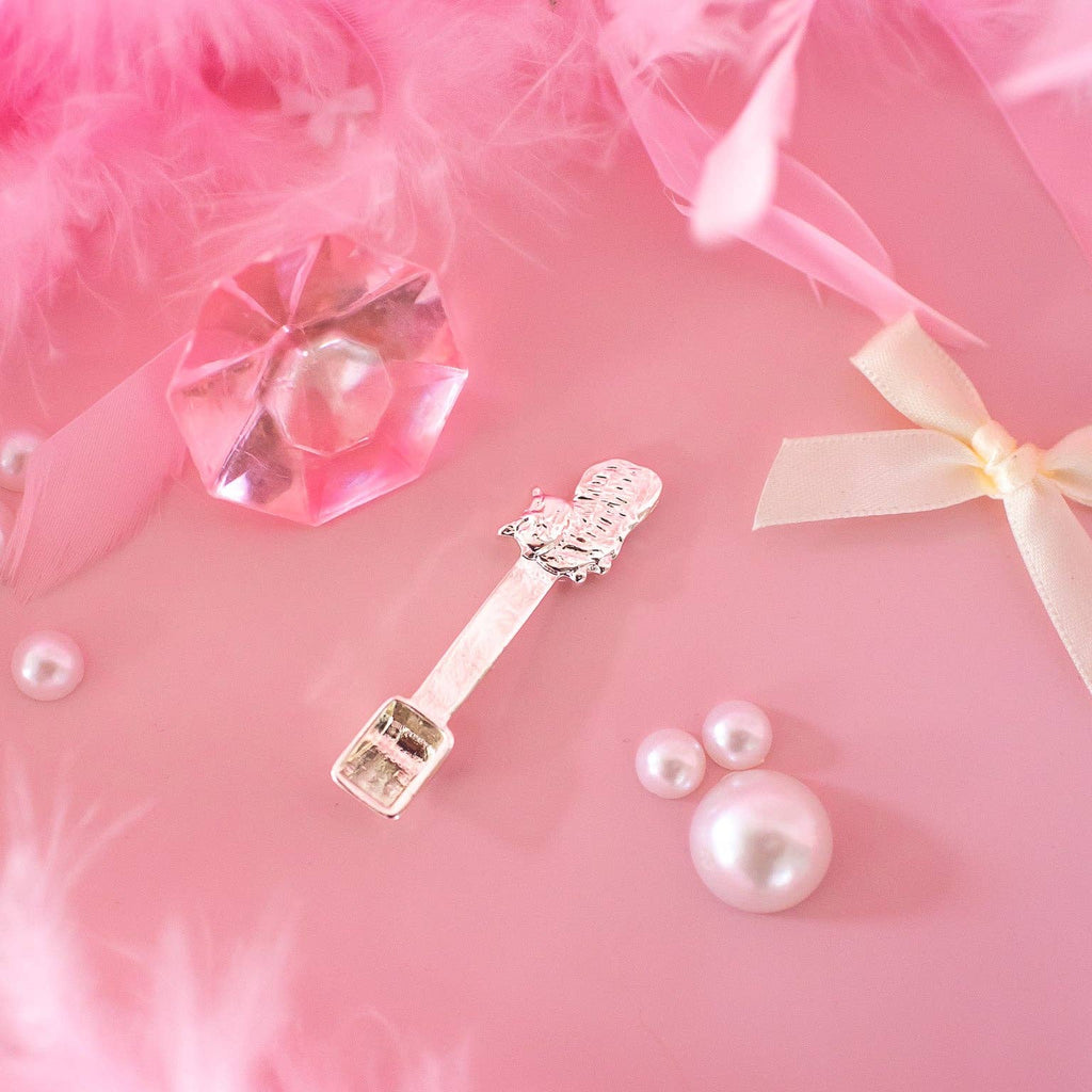 Silver key-shaped earring with crystals on a pink feather background