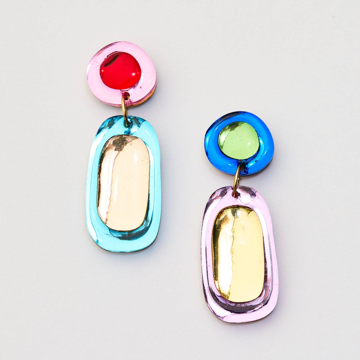 Colorful earrings with pink, red, blue, and gold on a light gray background