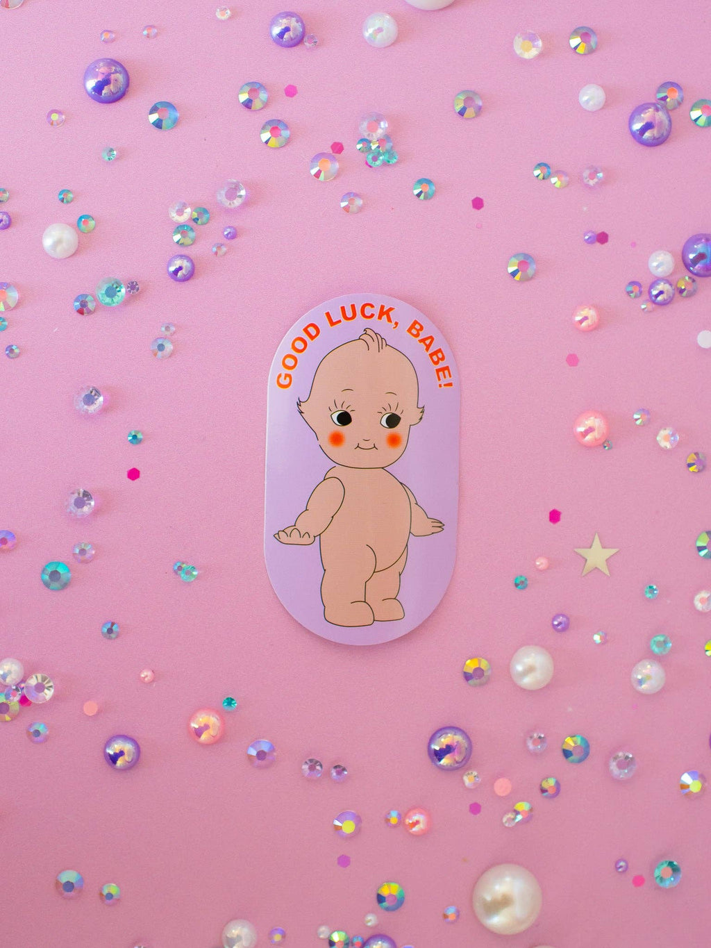 Sticker of a baby with 'Good Luck, Babe!' text on a pink background with confetti.