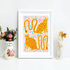 Framed colorful art print of cats on a white wall with decorative items.