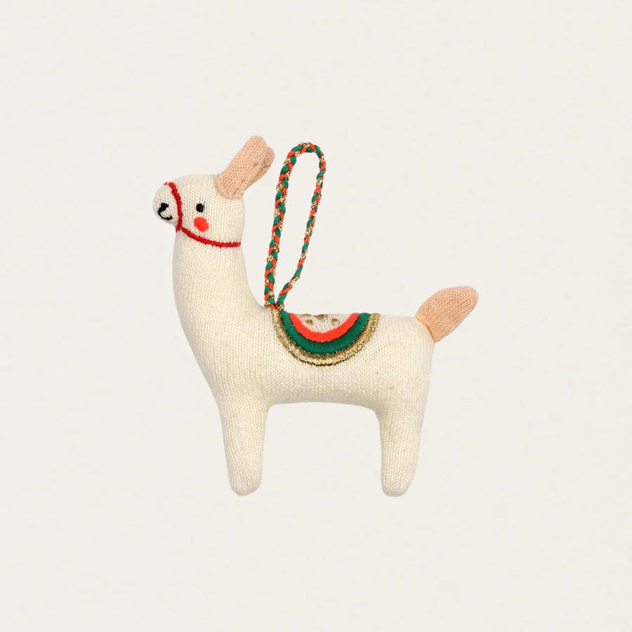 Knitted llama-shaped xmas decoration with a colorful strap on a light beige background
