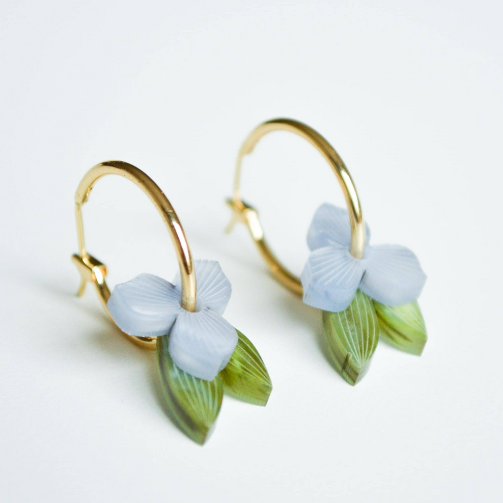 Gold hoop earrings with light blue floral designs on a white background