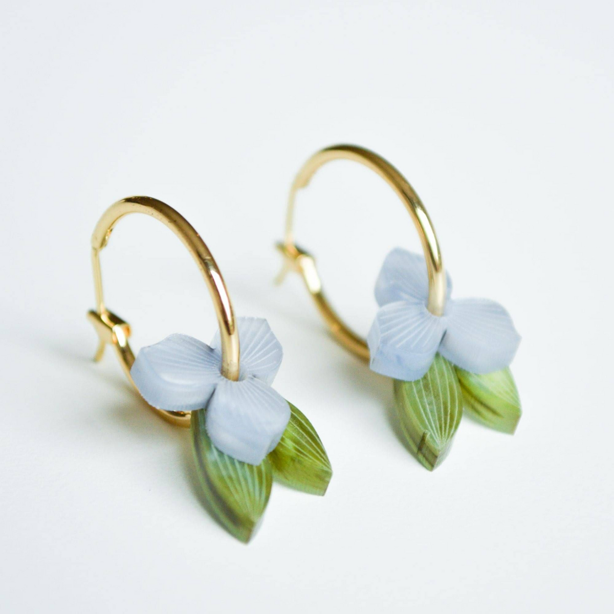 Gold hoop earrings with light blue floral designs on a white background