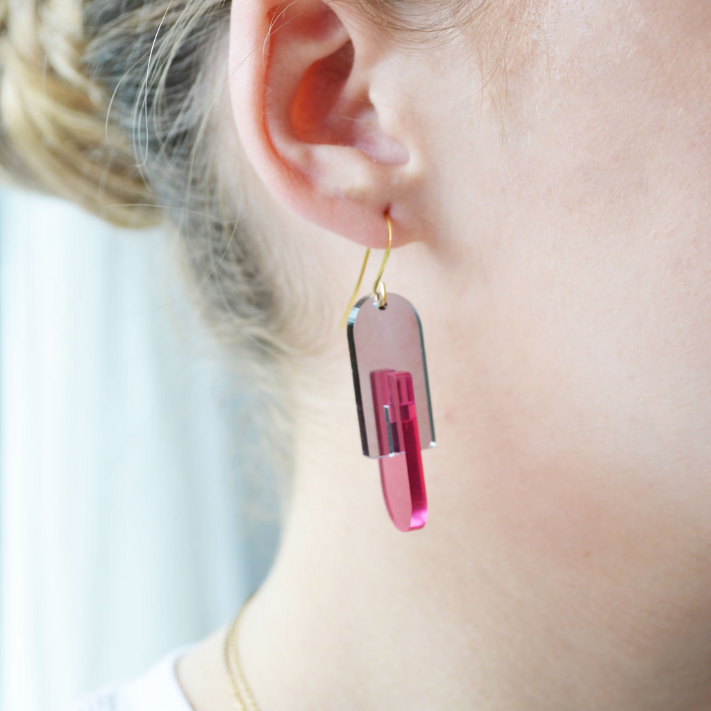 Close-up of a person wearing pink earrings with a blurred background
